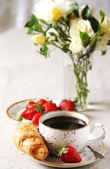 Breakfast. Croissant and strawberry. And black coffee, a bouquet of flowers. Fresh strawberries. 