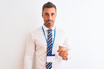 Young handsome business man wearing id pass and drinking coffee over isolated background with a confident expression on smart face thinking serious