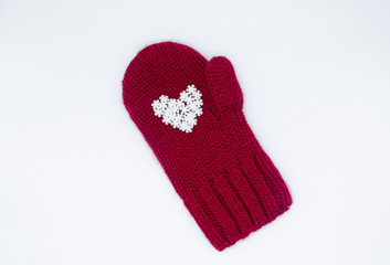 A knitted red mitten, on which white snowflakes in the shape of a heart lie as if in the palm of your hand on a white background, isolated. Сoncept of Christmas, winter, love, care and Valentine's day