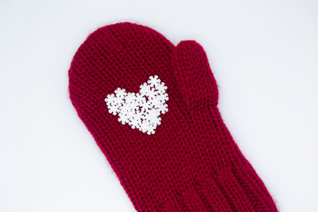 Close up of a knitted red mitten with white snowflakes in the shape of a heart on a white background, isolated. Сoncept of Christmas, winter, love, care and Valentine's day