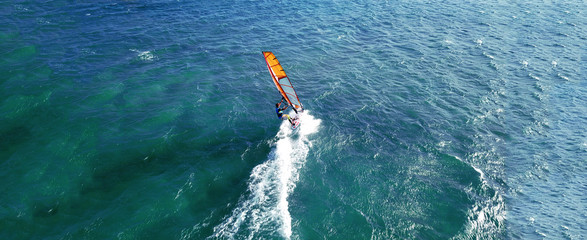 Aerial drone ultra wide photo of wind athlete surfer practising in deep blue open ocean sea