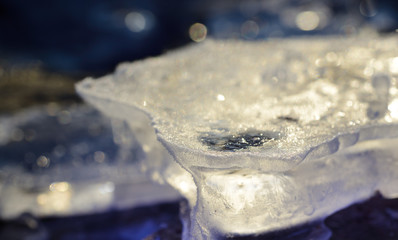 Closeup of frozen ice glistening in the sun outdoors in winter against blue background