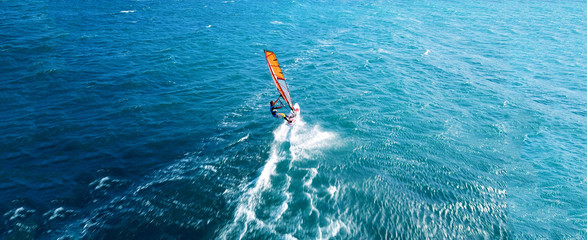 Aerial drone ultra wide photo of wind athlete surfer practising in deep blue open ocean sea