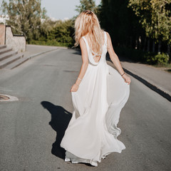 Fototapeta na wymiar young adult blonde in a white dress is spinning, feeling freedom