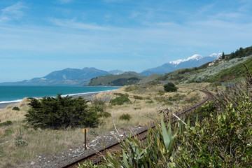 The main railway line on the east coast of the South Island of New Zealand, with the snow-capped Kaikoura Mountains in the background.