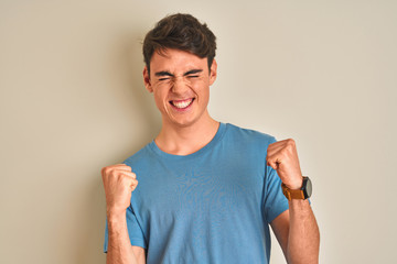 Teenager boy wearing casual t-shirt standing over isolated background very happy and excited doing...