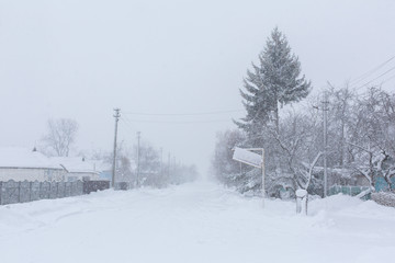 Winter, rural streets are covered with snow. Snow blizzard