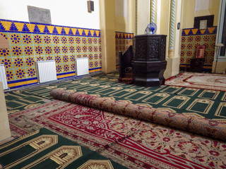 Prayer hall in a Turkish mosque with colored  carpets in Constanta, Romania, with colored  carpets.