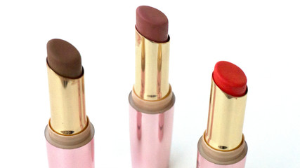 Brown and red lipsticks with pink cap on white background.