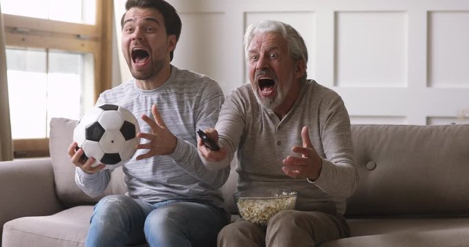 Funny overjoyed old father and young son watching football game