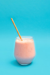 Fresh cold Strawberry Lassi drink in a glass cup with paper straw