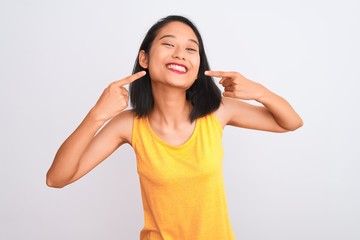 Obraz na płótnie Canvas Young chinese woman wearing yellow casual t-shirt standing over isolated white background smiling cheerful showing and pointing with fingers teeth and mouth. Dental health concept.