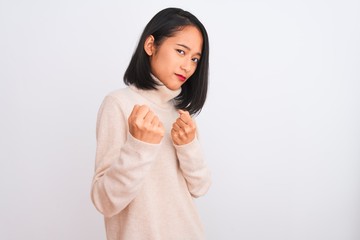 Young chinese woman wearing turtleneck sweater standing over isolated white background Ready to fight with fist defense gesture, angry and upset face, afraid of problem
