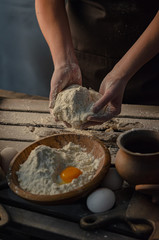 Thin graceful female hands a month dough. Dark Moody.