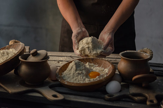 Thin graceful female hands a month dough. Dark Moody.