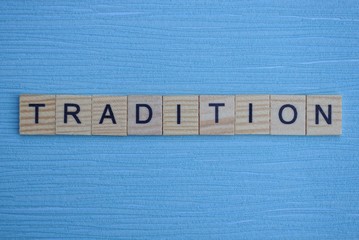  gray word tradition from small wooden letters on a blue table