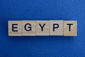  gray word egypt from small wooden letters on a blue table