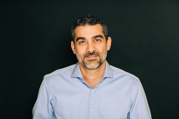 Studio portrait of handsome man wearing formal blue shirt, posing on black background