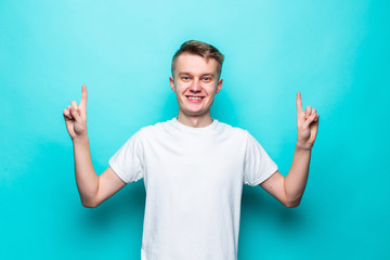 Young handsome man pointing upside with opened mouth against a green background