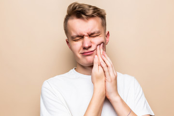 Young man suffering from toothache isolated on beige background