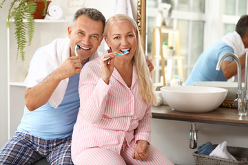 Mature couple brushing teeth at home