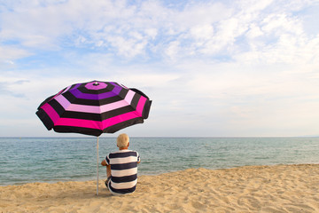 Fototapeta na wymiar Man under beach umbrella for shadow