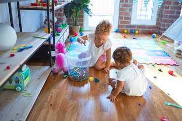 Beautiful toddlers playing around lots of toys at kindergarten