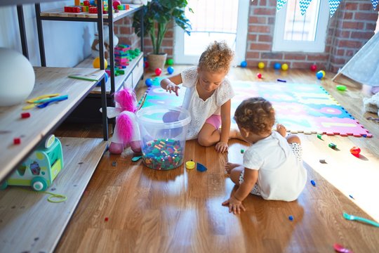 Beautiful toddlers playing around lots of toys at kindergarten