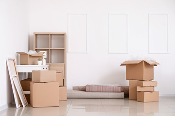 Cardboard boxes with belongings and furniture in new flat on moving day