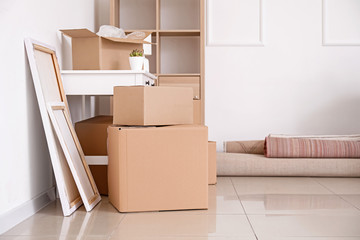 Cardboard boxes with belongings and furniture in new flat on moving day