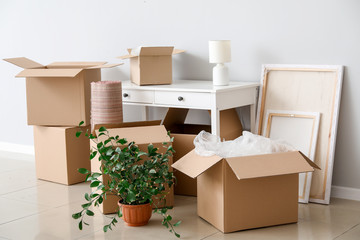 Cardboard boxes with belongings and table in new flat on moving day