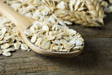 Heap of oat flakes in wooden spoon on rustic table, healthy eating vegetarian diet concept, selective focus