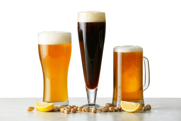 Glasses of different tasty beer with pistachio nuts on white background