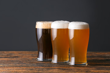 Glasses of different tasty beer on wooden table