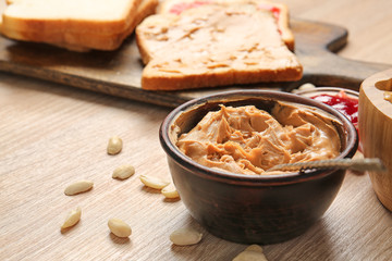Tasty peanut butter in bowl on wooden table