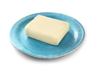 Plate with fresh butter on white background