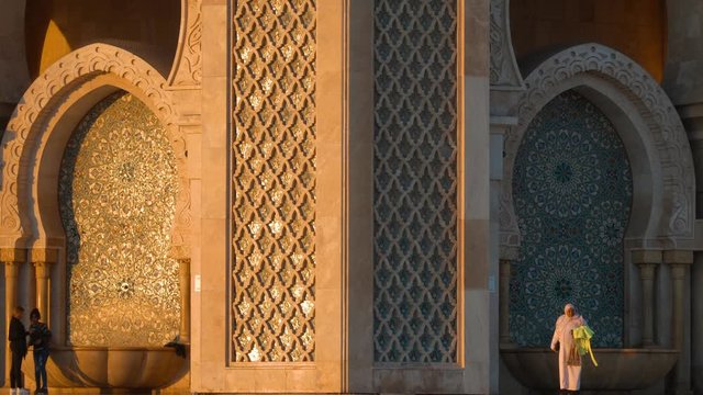 tourists walking by arches of Hassan II Mosque - travel destinations - Moroccan architecture