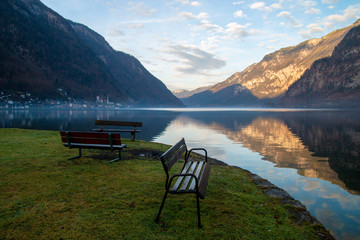 Peaceful landscape with park benches in front of calm lake and view of Hallstatt mountains village in Austria afternoon before sunset