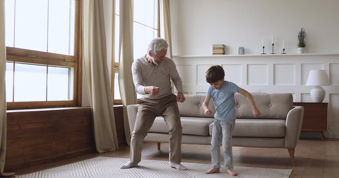 Happy two age generations active family dancing in living room