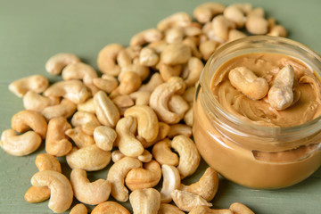 Jar of cashew butter on color background