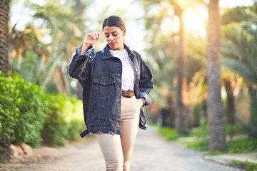 Young beautiful woman wearing denim jacket standing at the town park