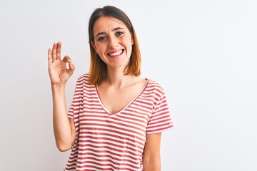 Beautiful redhead woman wearing casual striped red t-shirt over isolated background smiling positive doing ok sign with hand and fingers. Successful expression.