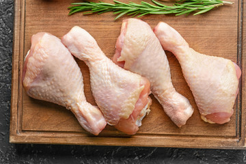 Raw chicken drumsticks on wooden board
