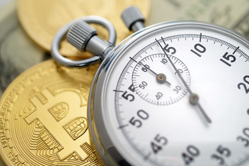 Physical golden bitcoin coins and mechanical analog stopwatch.