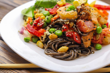 Tasty soba pasta with seafood and vegetables on wooden table