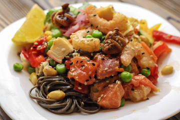 Tasty soba pasta with seafood and vegetables on wooden table