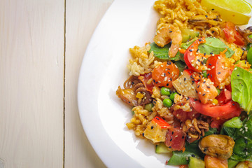 Plate with boiled rice, vegetables and seafood on table, close up
