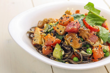 Tasty soba pasta with seafood and vegetables on wooden table