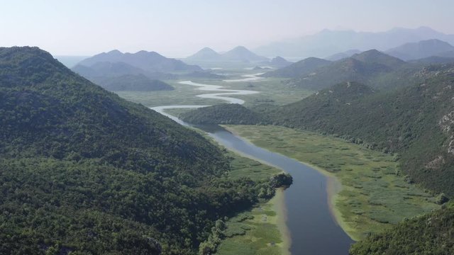 Camera up over water surface of River Rijeka Crnojevica. Turn of watercourse with beauty nature. Part of Skadar lake and national park in Montenegro