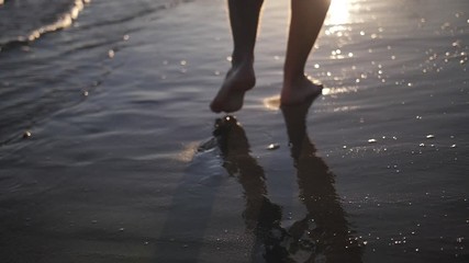 man walks along the coastline at sunset legs close-up slow motion - Powered by Adobe